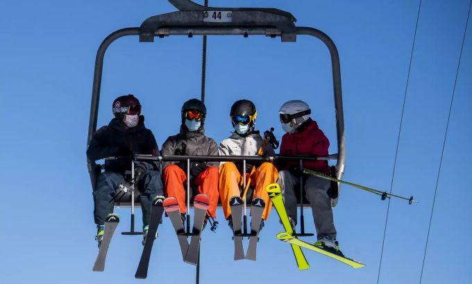 Skifahrer mit Gesichtsmasken fahren mit einem Sessellift am Eröffnungstag des Skigebiets Verbier in den Schweizer Alpen. verbier