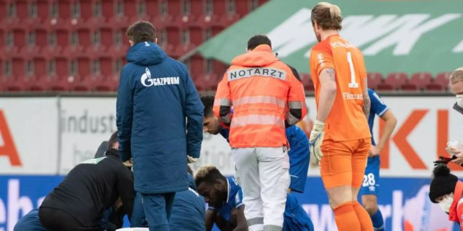 Ein Notarzt kümmert sich um Mark Uth. Die Verletzung des Schalke-Stürmers hat die Partie in Augsburg überschattet. Foto: Stefan Puchner/dpa