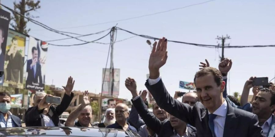 Baschar al-Assad (r), Präsident von Syrien, kommt an einem Wahllokal während der Präsidentschaftswahlen an. Foto: Hassan Ammar/AP/dpa