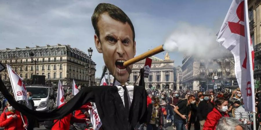 Demonstranten ziehen mit einem Zigarre rauchenden Abbild des französischen Präsidenten Macron durch Paris. Foto: Michel Euler/AP/dpa