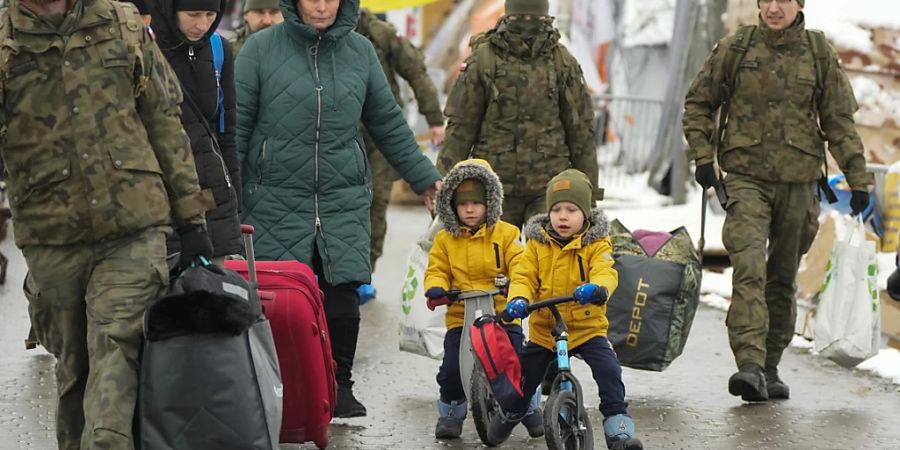 ARCHIV - Polnische Soldaten helfen einer Familie am polnisch-ukrainischen Grenzübergang Medyka bei der Rückkehr in die Ukraine. Foto: Sergei Grits/AP/dpa