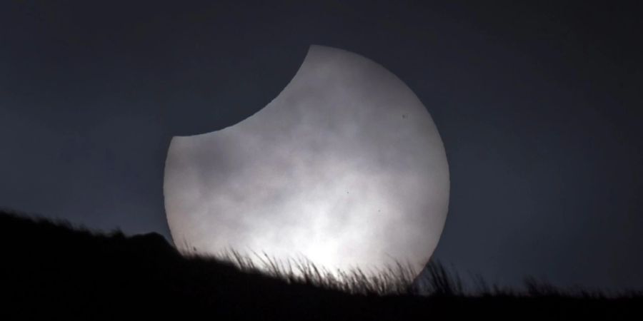 Die Sonne bricht während einer partiellen Sonnenfinsternis über Stoodley Pike in Grossbritannien durch die Wolken.