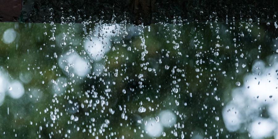 Statt zum Abfluss schiesst das Regenwasser während eines Unwetters an einer verstopften Regenrinne hinunter und sucht sich seinen Weg.