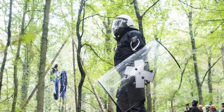 Polizisten stehen im September 2018 vor einer Barrikade im Hambacher Forst, in der sich eine Aktivistin festgebunden hat. Foto: Marcel Kusch/dpa