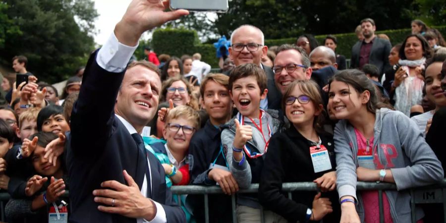 Emmanuel Macron macht ein Selfie mit Fans.