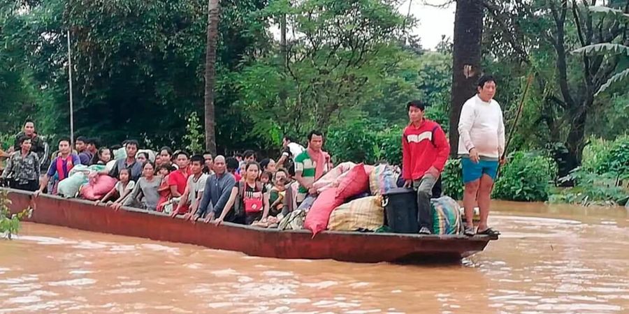 Nach dem Bruch eines Staudamms in Laos retten sich mehrere Menschen auf ein Boot.