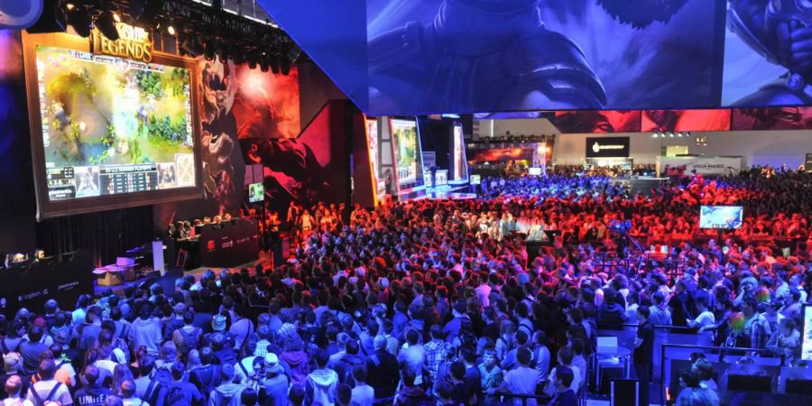 Eine Menschenmenge schaut sich ein League of Legends Spiel an der Gamescom an. Sie sind Rot und Blau beleuchtet.