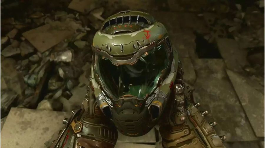 Doomslayer hält seinen Helm in den Händen. Er steht dabei auf einem kaputten Betonboden.