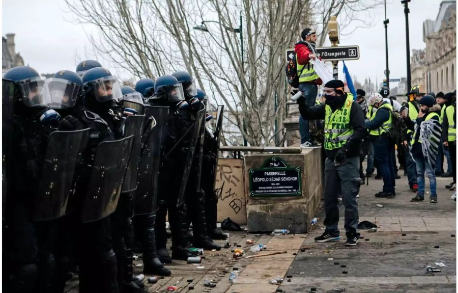 Polizisten stehen während eines Protests Demonstranten mit gelben Westen gegenüber.