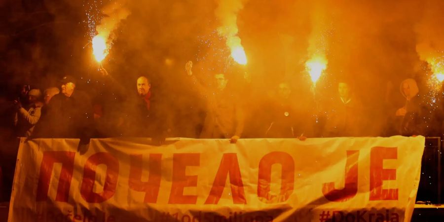 Demonstranten halten in Belgrad Fackeln und ein Banner.