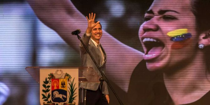 Juan Guaido winkt Studierende bei einer Rede zu.