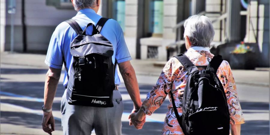 Zwei Senioren spazieren Hand in Hand durch die Strassen.