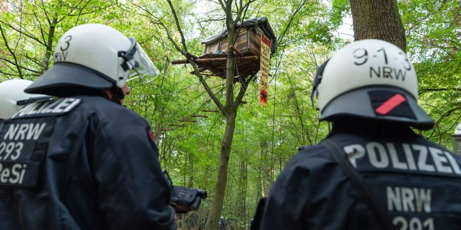 Zwei Polizisten stehen vor einem Baumhaus im Hambacher Forst.