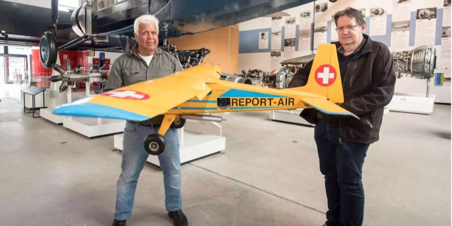 Der Luzerner Fotograf Niklaus Wächter mit einem mit Kameras ausgerüsteten Modellflugzeug, das er Damian Amstutz, Kurator Luft- und Raumfahrt (r.) im Verkehrshaus Luzern übergibt.