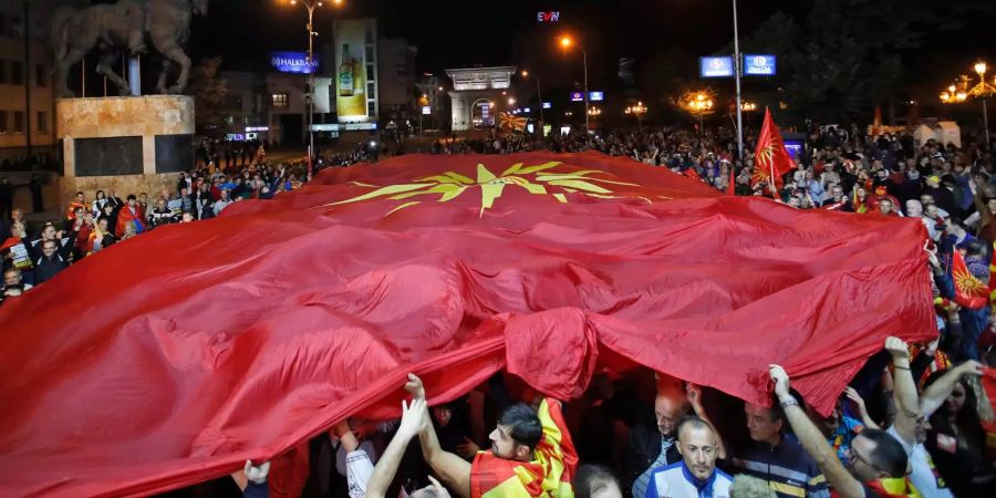 Nach dem Referendum gingen die Gegner der Namensänderung auf die Strasse und protestierten und hielten eine grosse Flagge von Mazedonien über sich.