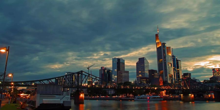 Die Wolkenkratzer in Frankfurt ragen bei Dämmerung in den bewölkten Himmel auf.