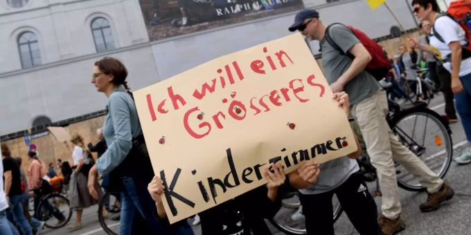 Teilnehmer einer Demonstration für bezahlbaren Wohnraum und gegen soziale Ausgrenzung unter dem Motto #ausspekuliert ziehen mit einem Plakat mit der Aufschrift «Ich will ein grösseres Kinderzimmer» durch die Ludwigsstrasse und gehen an einem grossen Werbeplakat an einer Hauswand vorbei. Teilnehmer einer Demonstration für bezahlbaren Wohnraum und gegen soziale Ausgrenzung unter dem Motto #ausspekuliert ziehen mit einem Plakat mit der Aufschrift «Ich will ein grösseres Kinderzimmer» durch die Ludwigsstrasse und gehen an einem grossen Werbeplakat an einer Hauswand vorbei.