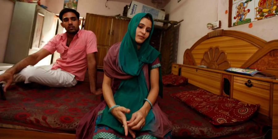 Ein Ehepaar aus Indien sitzt auf einem Bett.