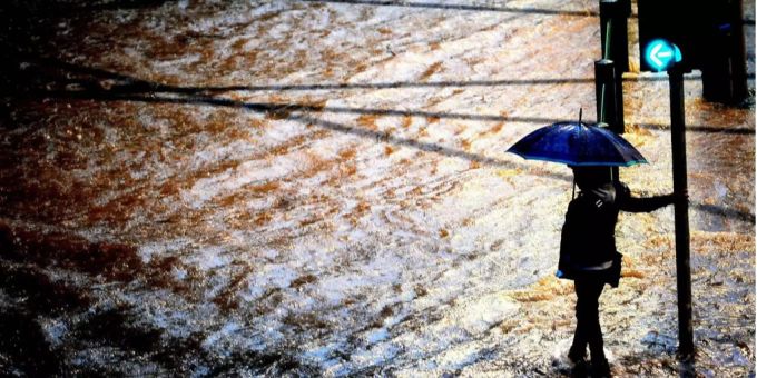 Eine Person vor einer mit Wasser überfluteten Strasse. (Symbolbild) unwetter