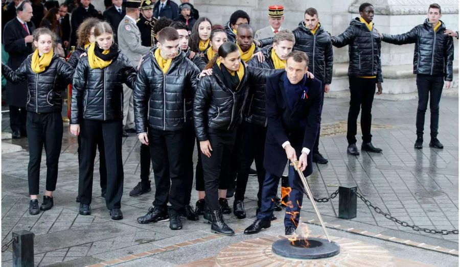 Emmanuel Macron, Präsident von Frankreich, entzündet mit Jugendlichen die ewige Flamme am Grab des unbekannten Soldaten