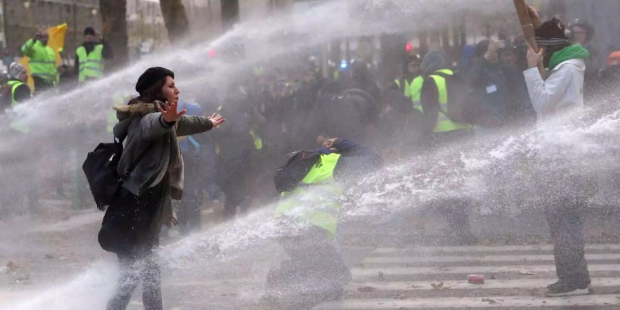 Eine Demonstrantin steht zwischen den Strahlen von Wasserwerfern bei einer Demonstration der «Gilets Jaunes».