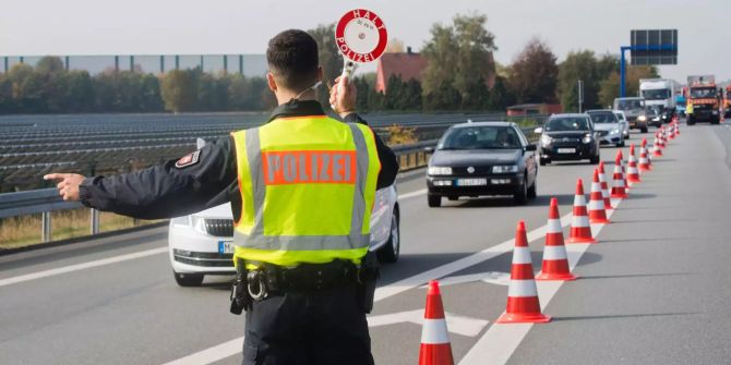 Ein Polizist winkt mit einer Polizeikelle bei einer Grosskontrolle an der Autobahn A30 im Landkreis Osnabrück Autos aus dem Verkehr.