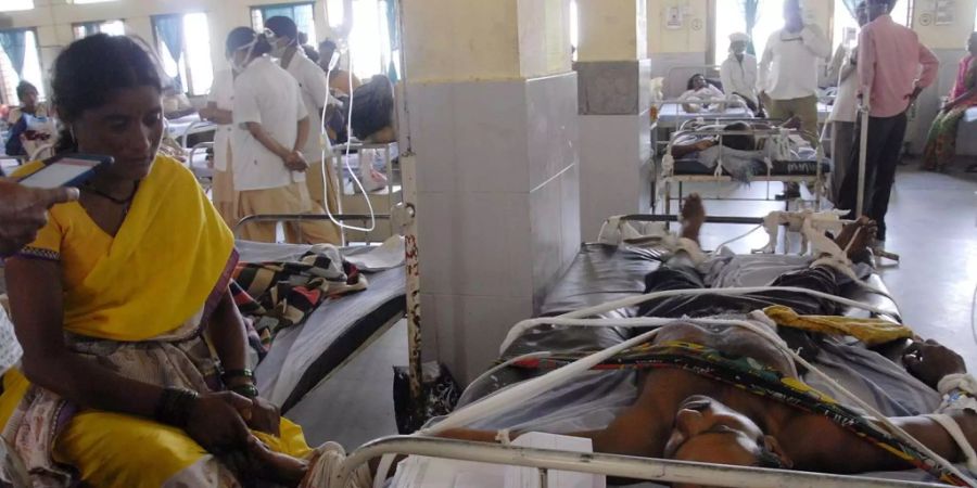 Mehrere Baumwollarbeiter werden aufgrund einer Pestizid-Vergiftung in einem staatlichen Spital in Yavatmal (IND) behandelt, daneben sind ihre Angehörigen.