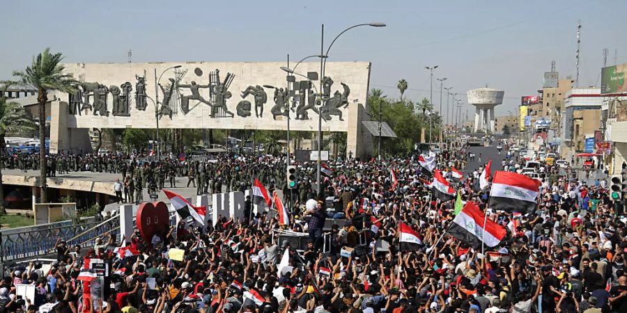 Menschen nehmen an einem regierungskritischen Protest auf dem Tahrir-Platz teil. Nach dem Tod eines bekannten politischen Aktivisten im Irak haben Tausende Demonstranten in der Hauptstadt Bagdad gefordert, die Verantwortlichen zur Rechenschaft zu ziehen. Foto: Hadi Mizban/AP/dpa Foto: Hadi Mizban/AP/dpa