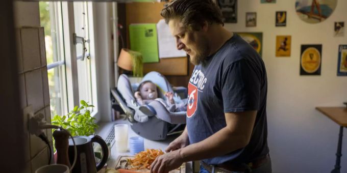 Ein Vater bereitet während seinem Vaterschaftsurlaub zu Hause Brei für seine Tochter zu. vaterschaftsurlaub