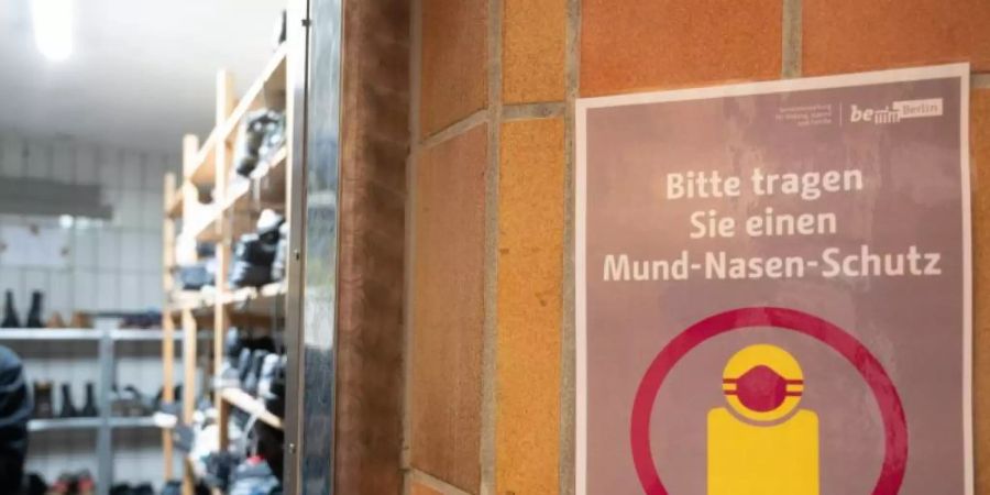 In der Kleiderkammer der Berliner Stadtmission hängt ein Plakat mit der Aufschrift „Bitte tragen Sie einen Mund-Nasen-Schutz“. Foto: Christophe Gateau/dpa