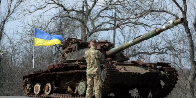 Ukrainischer Soldat vor einem zerstörten Panzer Ukrainischer Soldat vor einem zerstörten Panzer