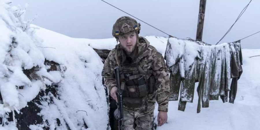 Ein ukrainischer Soldat in einem schneebedeckten Schützengraben bei Wodjane. Foto: Evgeniy Maloletka/AP/dpa