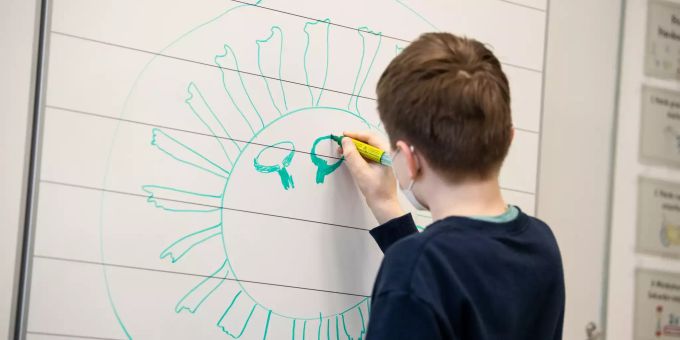 Ein Schüler einer vierten Klasse einer Grundschule zeichnet ein Corona-Virus an die Tafel. Coronavirus - Tests an Schule