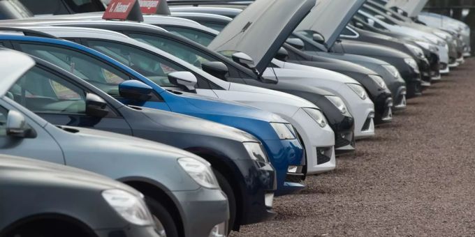 Neu- und Gebrauchtwagen stehen bei einem Autohändler nebeneinander. Autohändler