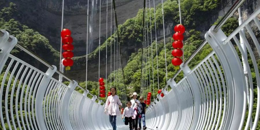 Touristen über eine Glasbrücke im Bezirk Zigui. Der Vorfall, bei dem ein Mann aus 100 Metern Höhe gerettet werden musste, heizt die Diskussion über die Sicherheit solcher Skywalks an. Foto: Wang Gang/XinHua/dpa