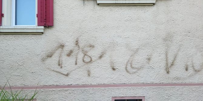 Grafitti an einer grauen Häuserfassade