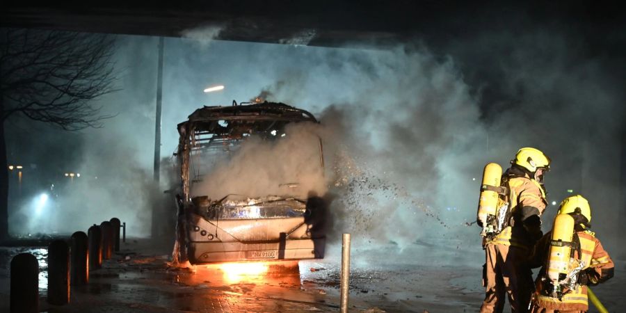 Feuerwehrmänner löschen an der Berliner Sonnenallee einen Reisebus, der von Unbekannten angezündet worden ist.