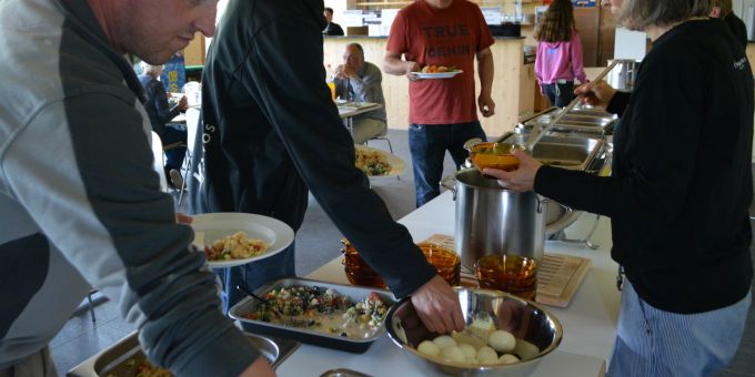 4Reasons mit Buffetsituation vom Mai 2022. Menschen bedienen sich an einem Buffet.