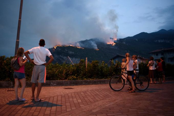 In Italien brennt es vielerorts aufgrund der Trockenheit: Einheimische beobachten, wie das Feuer am zweiten Tag der Brände in Nago (Südtirol) die Vegetation vernichtet. Aleksander Kalka/ZUMA Press Wire/dpa Waldbrand in Norditalien