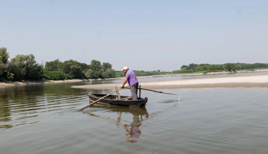 Ein Mann mit einem Boot auf dem Fluss Po, dessen Wasserstand sehr niedrig ist.