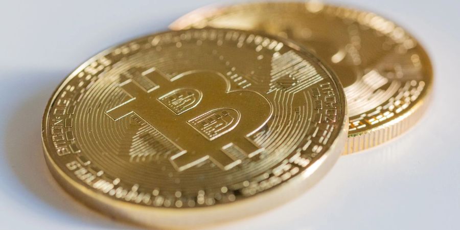 Zwei Bitcoin-Münzen liegen auf einem Tisch.