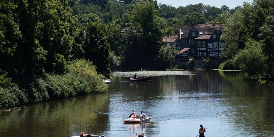 Stand-Up-Padler und Bootsfahrer sind in der Innenstadt von Marburg auf der Lahn unterwegs.