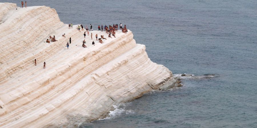 Menschen finden Komfort in der Meeresbrise auf der Scala dei Turchi, einer felsigen Klippe an der Küste von Realmonte im Süden Siziliens.