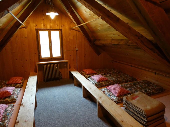 Wanderschuhe haben im Schlafsaal der Berghütte nichts zu suchen. Matratzen Berghütte Wolldecken Kissen Holz