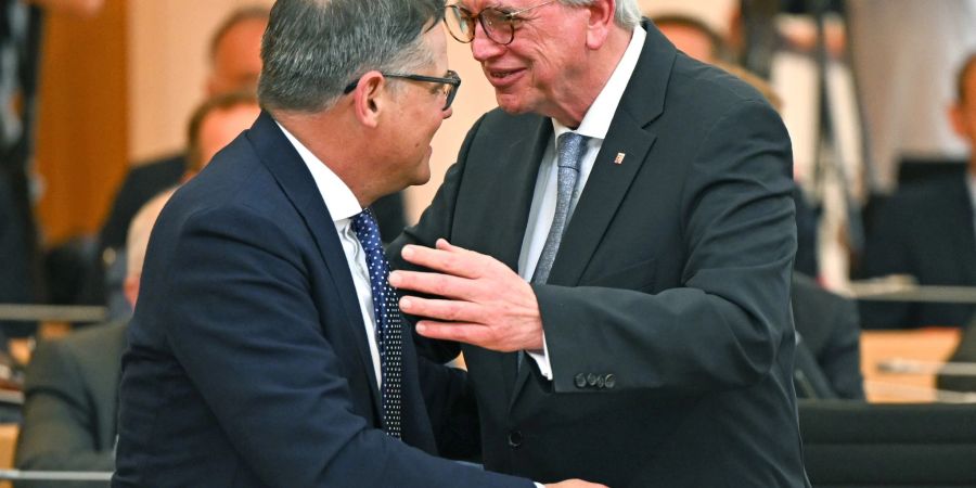 Boris Rhein (CDU, l), bisheriger Landtagspräsident und neuer Ministerpräsident in Hessen, umarmt seinen Amtsvorgänger Volker Bouffier (CDU) im Plenarsaal des hessischen Landtags nach dessen Rücktritt.
