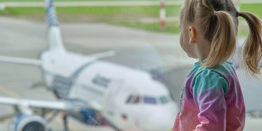 Mädchen schaut aus dem Fenster auf ein Flugzeug.