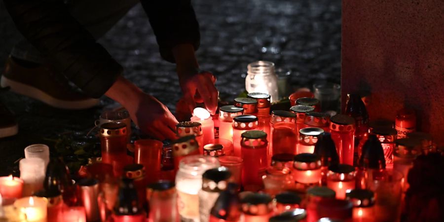 Eine Person entzündet eine Kerze vor dem Gebäude der Philosophischen Fakultät der Karls-Universität in Prag. Foto: Denes Erdos/AP/dpa