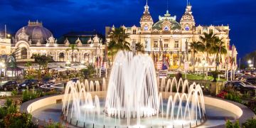 Beleuchteter Springbrunnen vor der Kulisee von den exklusiven Gebäuden in Monaco.