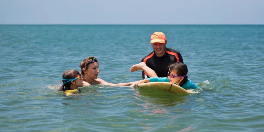 Kinder lernen Surfen im Meer.