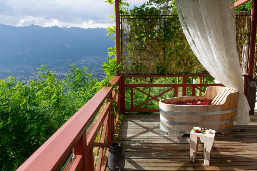 Holzbadewanne mit Blumen auf einem Balkon mit Ausblick.